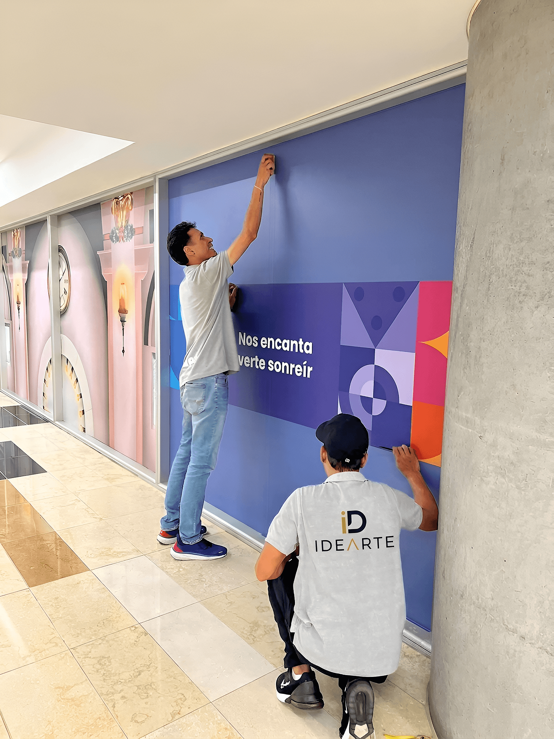 Equipo de Idearte instalando un mural en vinilo dentro de un centro comercial